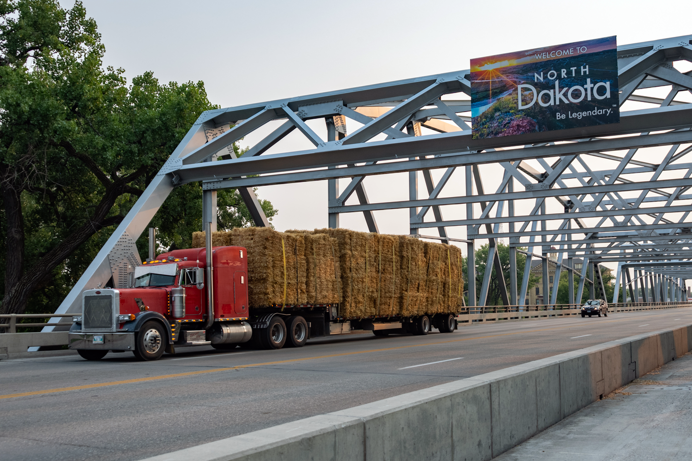 Semi truck hauling bails of hay crosses the North Dakota border into Minnesota.
