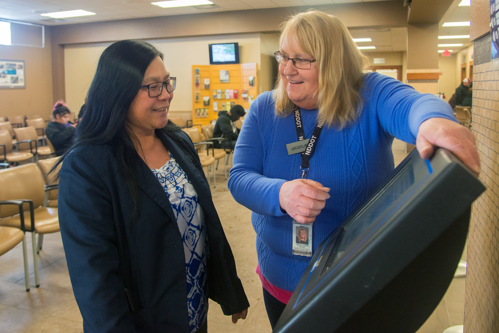 NDDOT employee helps woman renew her tags at a kiosk.